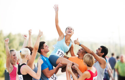 Female runner being held up after winning a race